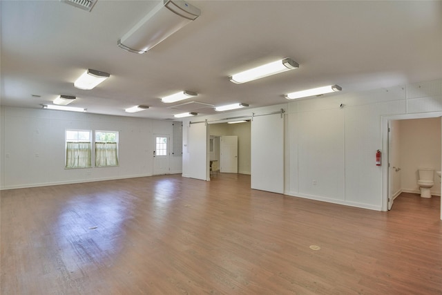 6495 Smoky Hill Ct, Granbury, TX 76049 - spare room with a barn door, light wood-style flooring, and baseboards
