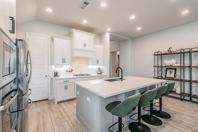 1704 Cypress Gap Trl, Mansfield, TX 76063 - kitchen featuring stainless steel appliances, a sink, light wood-type flooring, backsplash, and white cabinetry