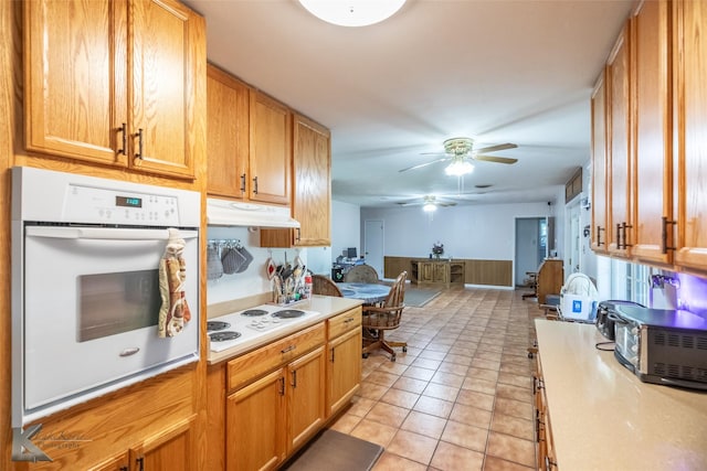 1602 Westwood Dr, Abilene, TX 79603 - kitchen with white appliances, light countertops, a ceiling fan, under cabinet range hood, and light tile patterned floors