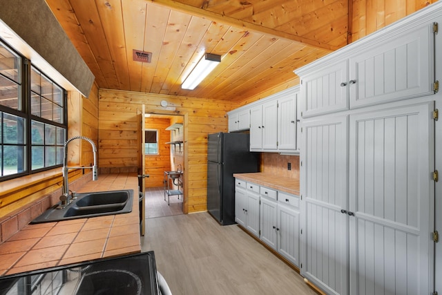 201 Cemetery Rd, Boyd, TX 76023 - kitchen with tile countertops, freestanding refrigerator, white cabinets, wood ceiling, and light wood finished floors
