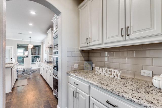 6829 Fire Dance Dr, Benbrook, TX 76126 - kitchen with arched walkways, white cabinetry, dark wood-style flooring, backsplash, and ornamental molding