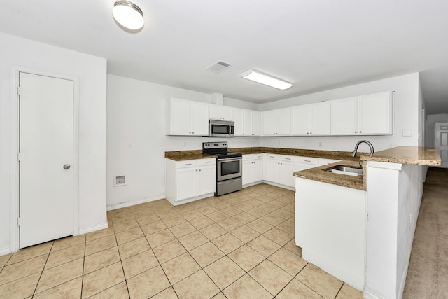 6021 Lucas Ct, Fort Worth, TX 76119 - kitchen with stainless steel appliances, a sink, a peninsula, and white cabinetry