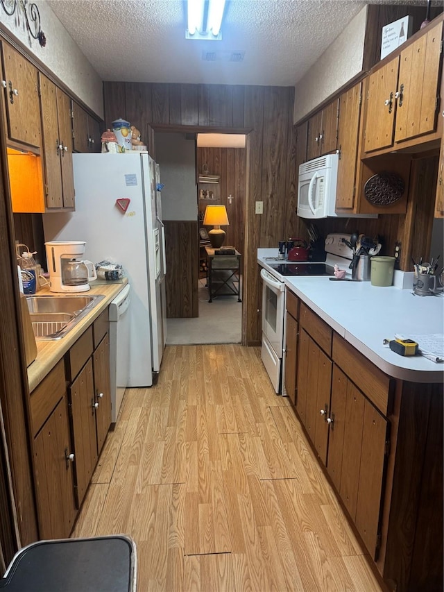 1614 Savage Dr, Mesquite, TX 75149 - kitchen with white appliances, light wood-style floors, light countertops, a textured ceiling, and a sink