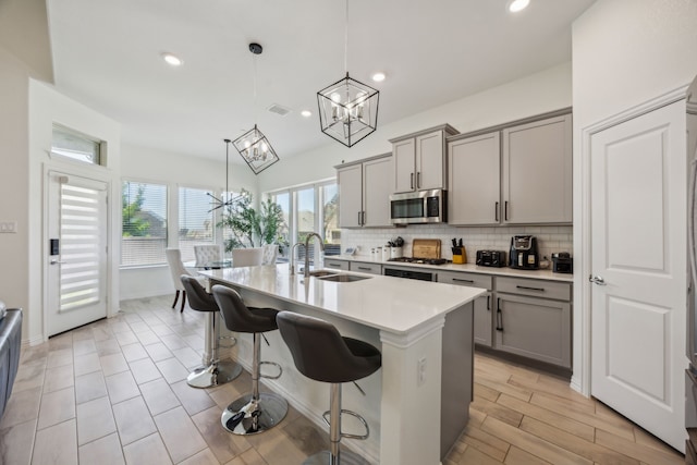 2004 Creekridge Dr, Lewisville, TX 75010 - kitchen with gray cabinets, appliances with stainless steel finishes, a chandelier, decorative backsplash, and a sink