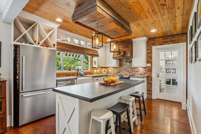 3227 Macarthur Dr, Waco, TX 76708 - kitchen featuring stainless steel appliances, wooden ceiling, a sink, dark countertops, and custom range hood
