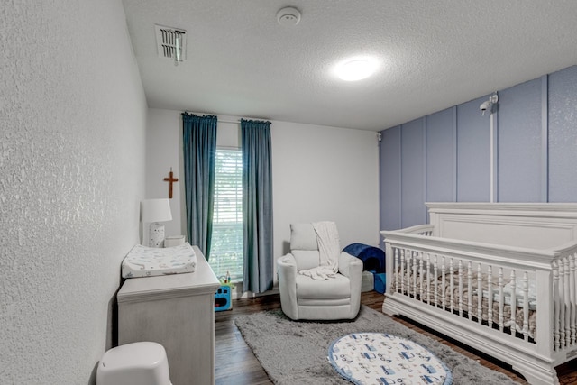 3510 Knoll Point Dr, Garland, TX 75043 - bedroom featuring a textured wall, a textured ceiling, wood finished floors, and a crib