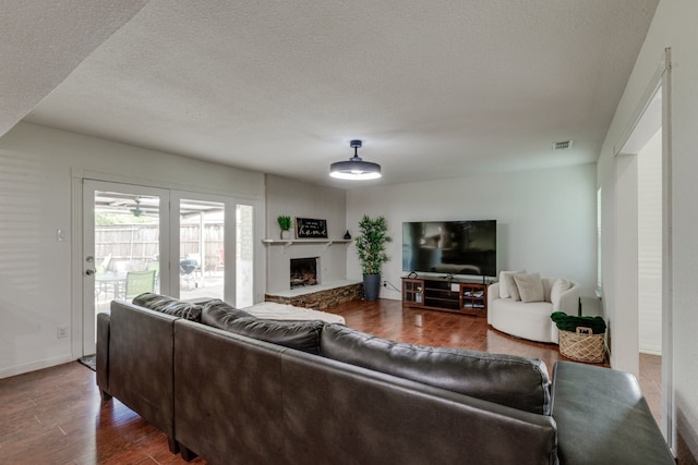 3510 Knoll Point Dr, Garland, TX 75043 - living area with dark wood finished floors, a textured ceiling, a fireplace with raised hearth, and baseboards
