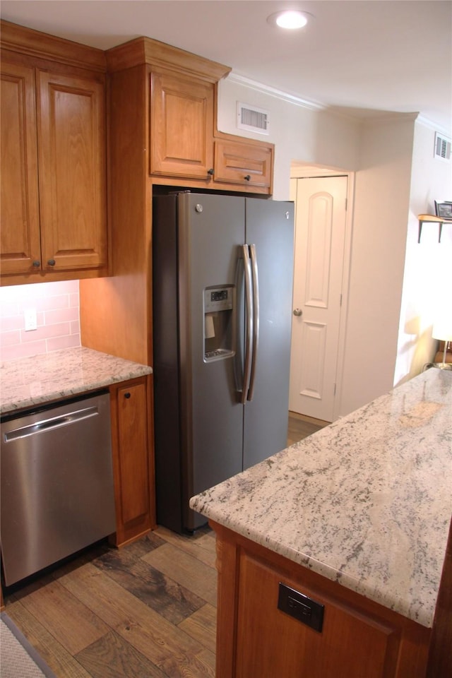 4320 Holland Ave Unit 202, Dallas, TX 75219 - kitchen with stainless steel appliances, light stone counters, dark wood-style flooring, backsplash, and brown cabinets