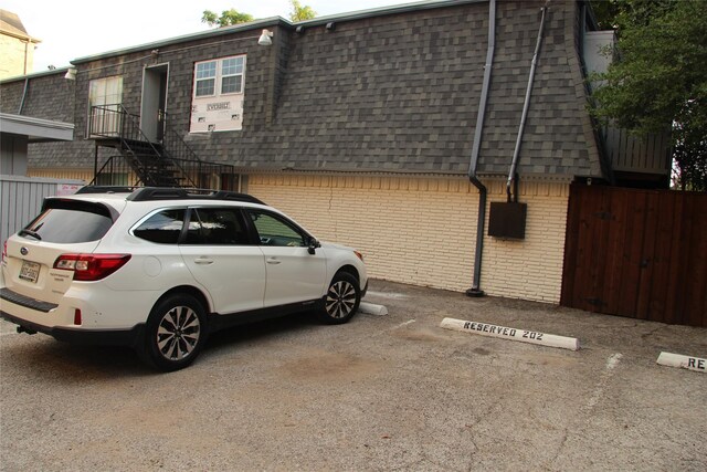 4320 Holland Ave Unit 202, Dallas, TX 75219 - view of property exterior featuring a shingled roof, mansard roof, brick siding, and uncovered parking