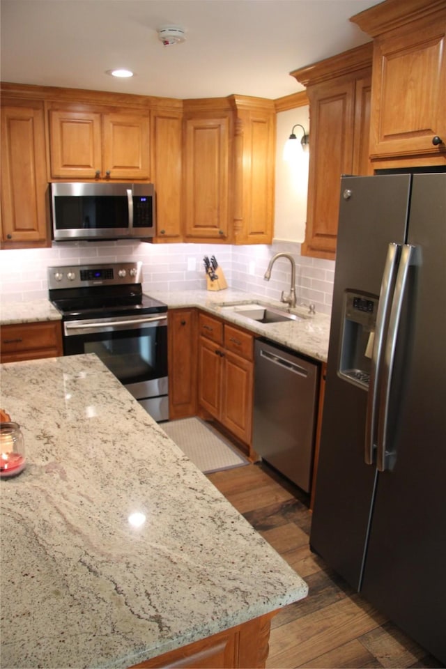 4320 Holland Ave Unit 202, Dallas, TX 75219 - kitchen with appliances with stainless steel finishes, a sink, backsplash, light stone countertops, and wood finished floors