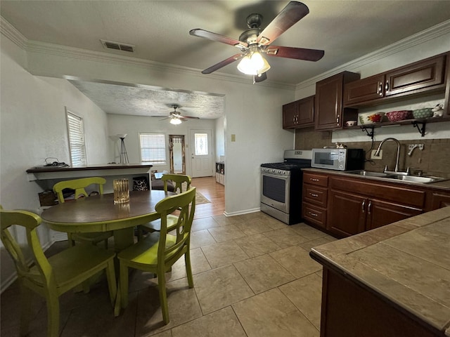 1206 S Crockett Dr, Abilene, TX 79605 - kitchen featuring gas range, white microwave, a sink, ceiling fan, and backsplash