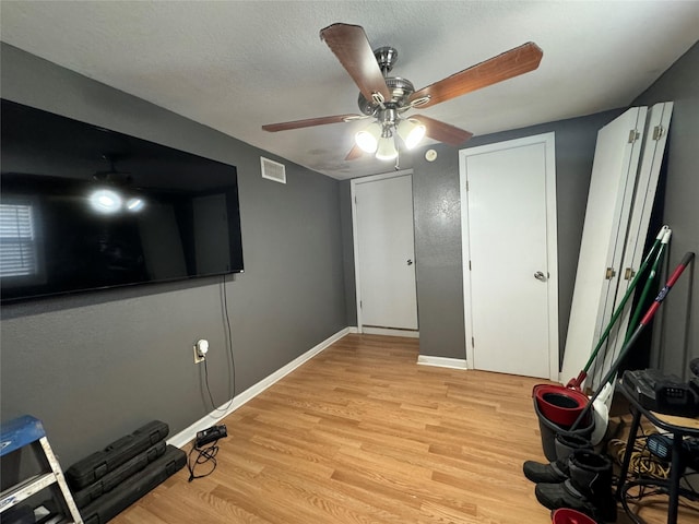 1206 S Crockett Dr, Abilene, TX 79605 - workout room with light wood-style flooring, ceiling fan, baseboards, and a textured ceiling