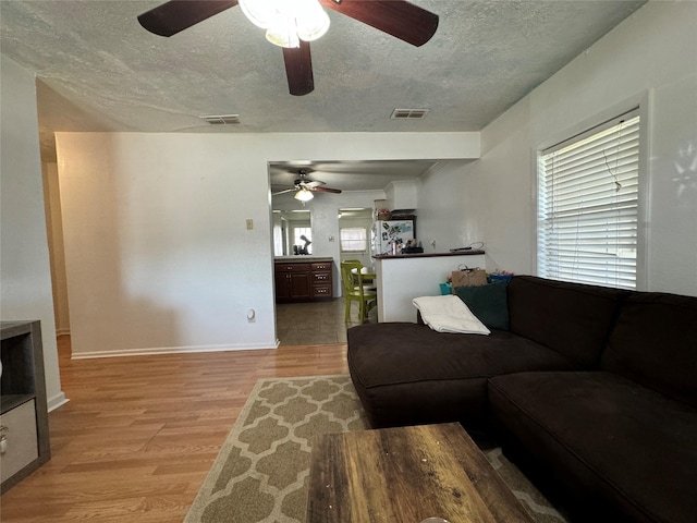 1206 S Crockett Dr, Abilene, TX 79605 - living room featuring a textured ceiling, ceiling fan, light wood-style floors, and baseboards