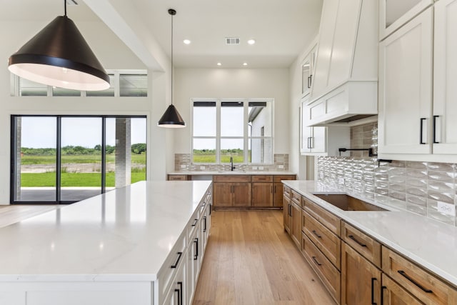 1324 Streetman Rd, Royse City, TX 75189 - kitchen featuring brown cabinetry, a sink, black electric stovetop, light wood-style flooring, and decorative backsplash