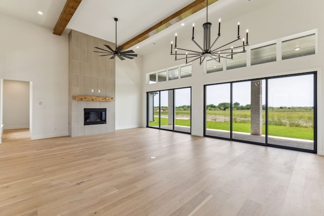 1324 Streetman Rd, Royse City, TX 75189 - unfurnished living room featuring a high ceiling, beamed ceiling, light wood-style flooring, a tiled fireplace, and a chandelier