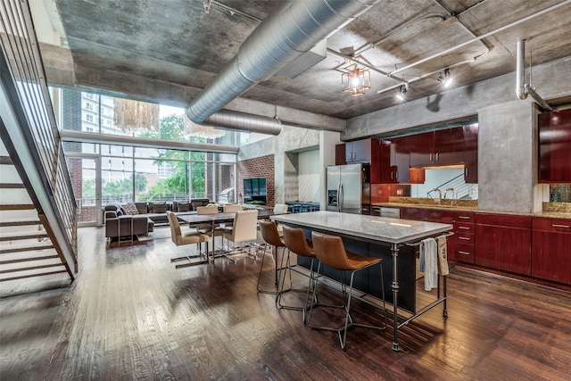 2011 Cedar Springs Rd Unit 106, Dallas, TX 75201 - kitchen with appliances with stainless steel finishes, dark wood finished floors, open floor plan, a kitchen island, and reddish brown cabinets