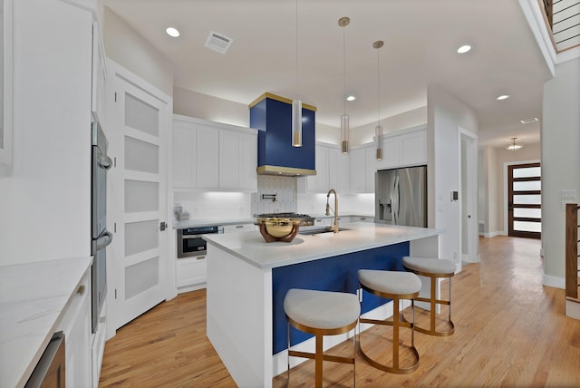 404 Bobbie St, Dallas, TX 75203 - kitchen with stainless steel appliances, a sink, a breakfast bar, an island with sink, and white cabinetry