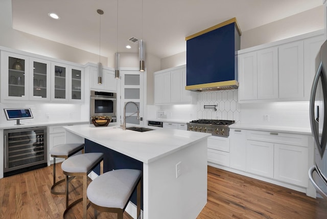 404 Bobbie St, Dallas, TX 75203 - kitchen with beverage cooler, appliances with stainless steel finishes, a sink, decorative backsplash, and a kitchen breakfast bar