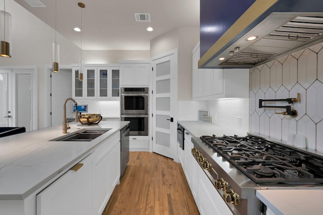 404 Bobbie St, Dallas, TX 75203 - kitchen featuring wall chimney exhaust hood, a sink, stainless steel appliances, white cabinetry, and tasteful backsplash
