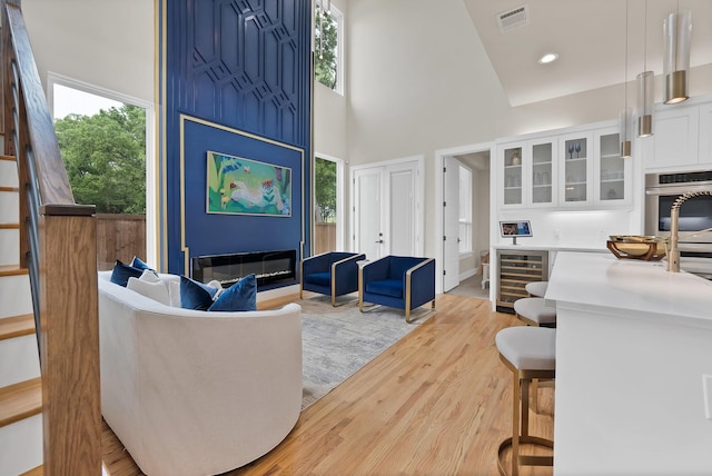 404 Bobbie St, Dallas, TX 75203 - living area featuring beverage cooler, light wood finished floors, a high ceiling, and plenty of natural light