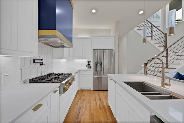 404 Bobbie St, Dallas, TX 75203 - kitchen featuring appliances with stainless steel finishes, wall chimney range hood, a sink, light wood-style flooring, and tasteful backsplash