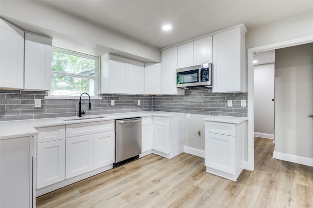 1326 Taperwicke Dr, Dallas, TX 75232 - kitchen with stainless steel appliances, a sink, light wood-style floors, and decorative backsplash