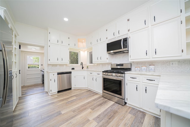 107 W Myrtle, Winnsboro, TX 75494 - kitchen featuring stainless steel appliances, white cabinetry, tasteful backsplash, light wood-style flooring, and a sink