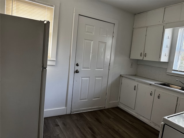 2958 Russell Ave, Abilene, TX 79605 - kitchen with freestanding refrigerator, a sink, dark wood-style flooring, white cabinetry, and light countertops