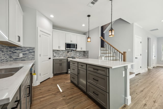 4002 Robert L Parish Sr Ave, Dallas, TX 75210 - kitchen featuring appliances with stainless steel finishes, gray cabinetry, dark wood-style flooring, backsplash, and white cabinetry