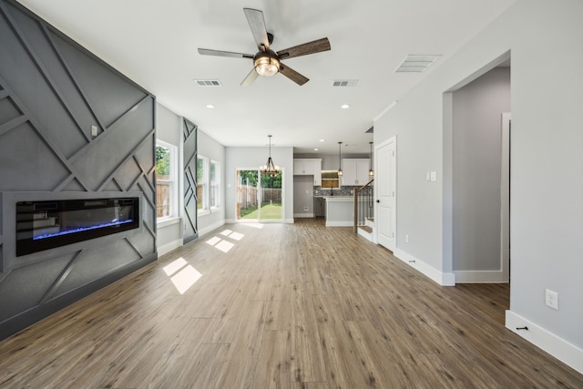 4002 Robert L Parish Sr Ave, Dallas, TX 75210 - unfurnished living room with a glass covered fireplace, wood finished floors, ceiling fan, baseboards, and a chandelier