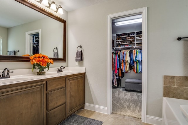 921 Yarwood Way, Burleson, TX 76028 - bathroom with double vanity, a walk in closet, a bath, tile patterned floors, and baseboards