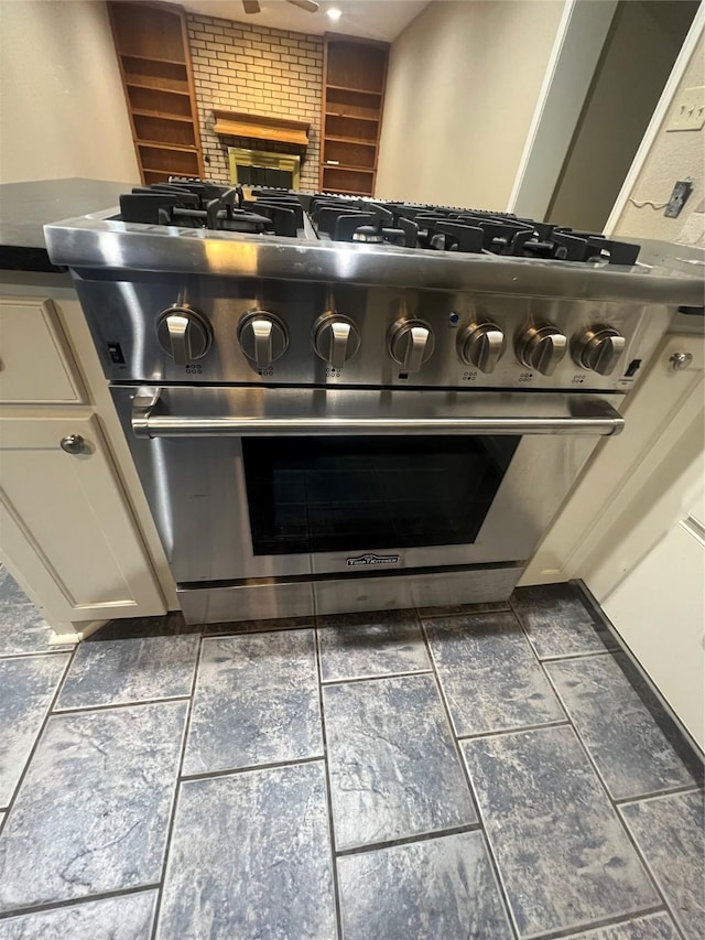 332 Belmont St, Hurst, TX 76053 - kitchen view of stainless steel range, a fireplace, dark countertops, and white cabinetry