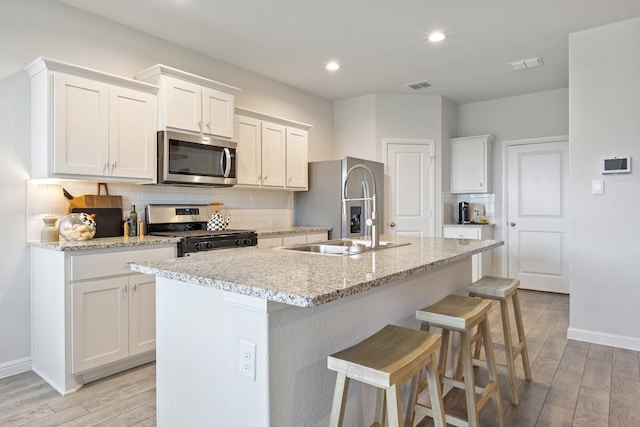 140 Orchard Pines Pl, Boyd, TX 76023 - kitchen featuring appliances with stainless steel finishes, light wood-style flooring, a kitchen island with sink, tasteful backsplash, and recessed lighting