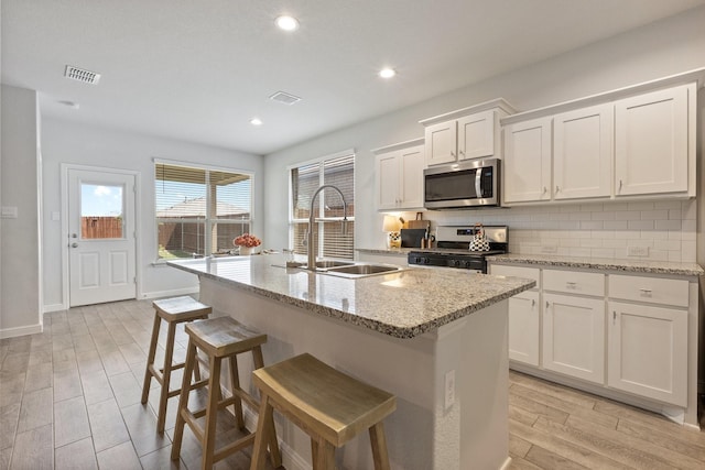 140 Orchard Pines Pl, Boyd, TX 76023 - kitchen featuring appliances with stainless steel finishes, a sink, wood finish floors, backsplash, and white cabinets