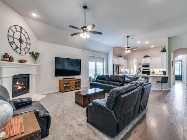2201 Mountain Creek Ct, Wylie, TX 75098 - living area featuring arched walkways, a ceiling fan, healthy amount of natural light, a glass covered fireplace, and lofted ceiling