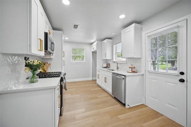 3651 Cindy Dr, Fort Worth, TX 76111 - kitchen featuring stainless steel appliances, a sink, white cabinetry, light countertops, and light wood-type flooring