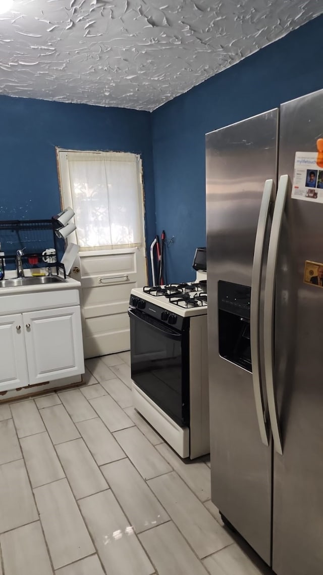 5612 Wainwright Dr, Fort Worth, TX 76112 - kitchen featuring stainless steel fridge, gas range oven, a sink, and white cabinets