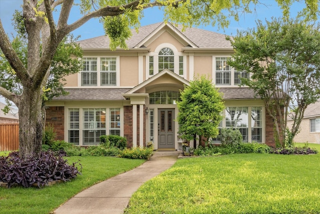 1811 Whitney Dr, Richardson, TX 75082 - traditional-style house featuring stucco siding, a front yard, a shingled roof, and brick siding