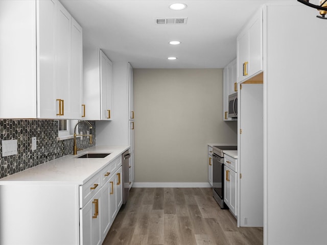 1013 Nueva Tierra St, Grand Prairie, TX 75052 - kitchen with a sink, appliances with stainless steel finishes, white cabinets, light wood-style flooring, and recessed lighting