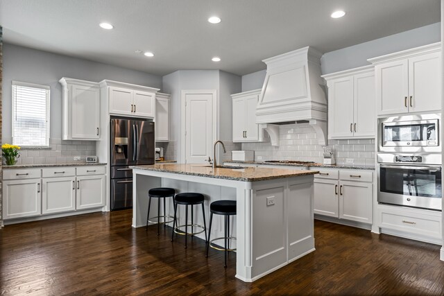 1020 Highpoint Way, Roanoke, TX 76262 - kitchen with stainless steel appliances, custom range hood, a sink, backsplash, and a kitchen island with sink