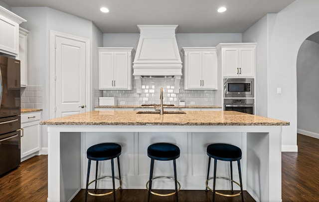 1020 Highpoint Way, Roanoke, TX 76262 - kitchen with appliances with stainless steel finishes, a sink, premium range hood, an island with sink, and backsplash
