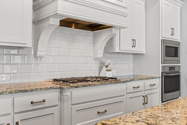 1020 Highpoint Way, Roanoke, TX 76262 - kitchen featuring appliances with stainless steel finishes, white cabinetry, decorative backsplash, and light stone counters