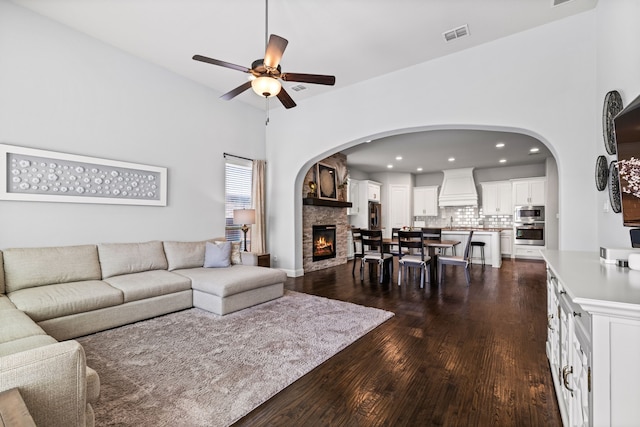 1020 Highpoint Way, Roanoke, TX 76262 - living area with dark wood-style flooring, ceiling fan, a fireplace, recessed lighting, and arched walkways