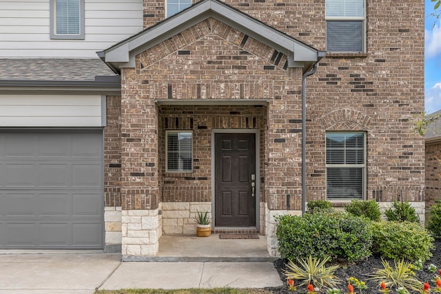 10613 Dolostone Ct, Fort Worth, TX 76108 - view of exterior entry with brick siding, an attached garage, stone siding, and roof with shingles