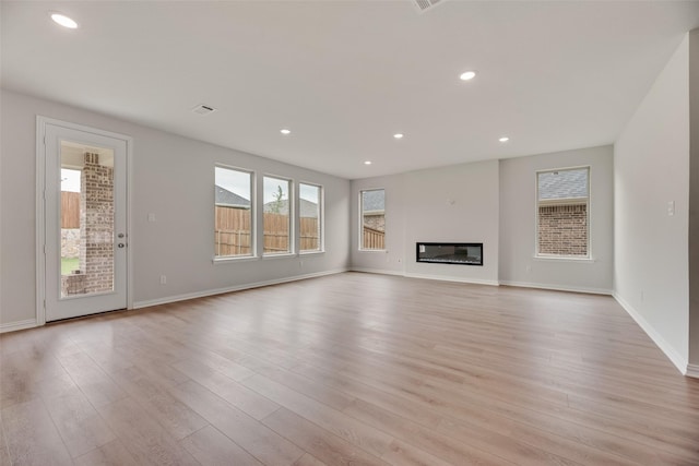 3229 Loftwood Ln, Anna, TX 75409 - unfurnished living room with light wood-type flooring, recessed lighting, and a glass covered fireplace
