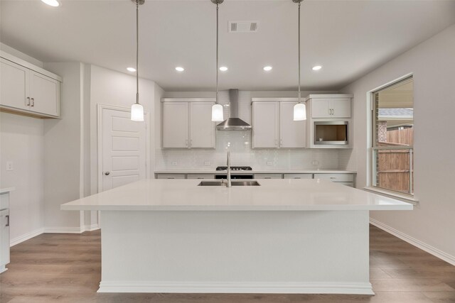 3229 Loftwood Ln, Anna, TX 75409 - kitchen with wall chimney exhaust hood, backsplash, wood finished floors, light countertops, and decorative light fixtures