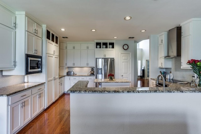 431 Lakefield Dr, Murphy, TX 75094 - kitchen featuring stainless steel appliances, wall chimney range hood, a peninsula, dark stone countertops, and dark wood-type flooring