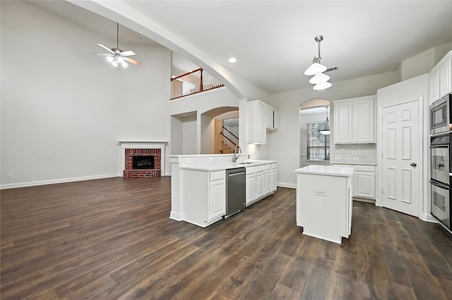 3816 Appleton Ln, Flower Mound, TX 75022 - kitchen with stainless steel appliances, a fireplace, ceiling fan, arched walkways, and light countertops