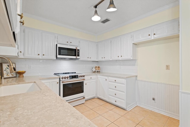 132 Cherrybark Dr, Coppell, TX 75019 - kitchen with white appliances, a sink, white cabinets, a wainscoted wall, and light tile patterned flooring