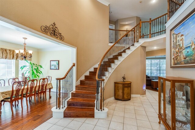 8017 Stonehill Dr, Plano, TX 75025 - stairs featuring a chandelier, ornamental molding, a towering ceiling, baseboards, and tile patterned floors